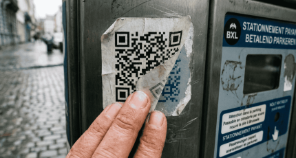 Close-up van een hand die een loslatende, valse QR-code sticker op een Belgische parkeerautomaat controleert. Dit illustreert de fysieke 'voel-test' om 'quishing' te herkennen, zoals geadviseerd door Cyberplan.